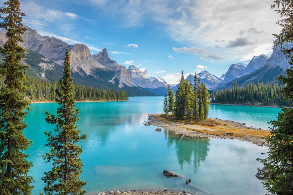 Jasper National Park, Canada - blue river with tall mountain and trees surrounding.