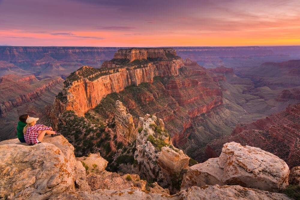 Couple sitting on cliffside in Grand Canyon National Park, Arizona