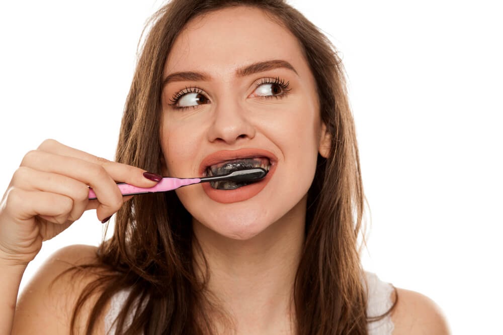Girl brushing teeth with activated charcoal