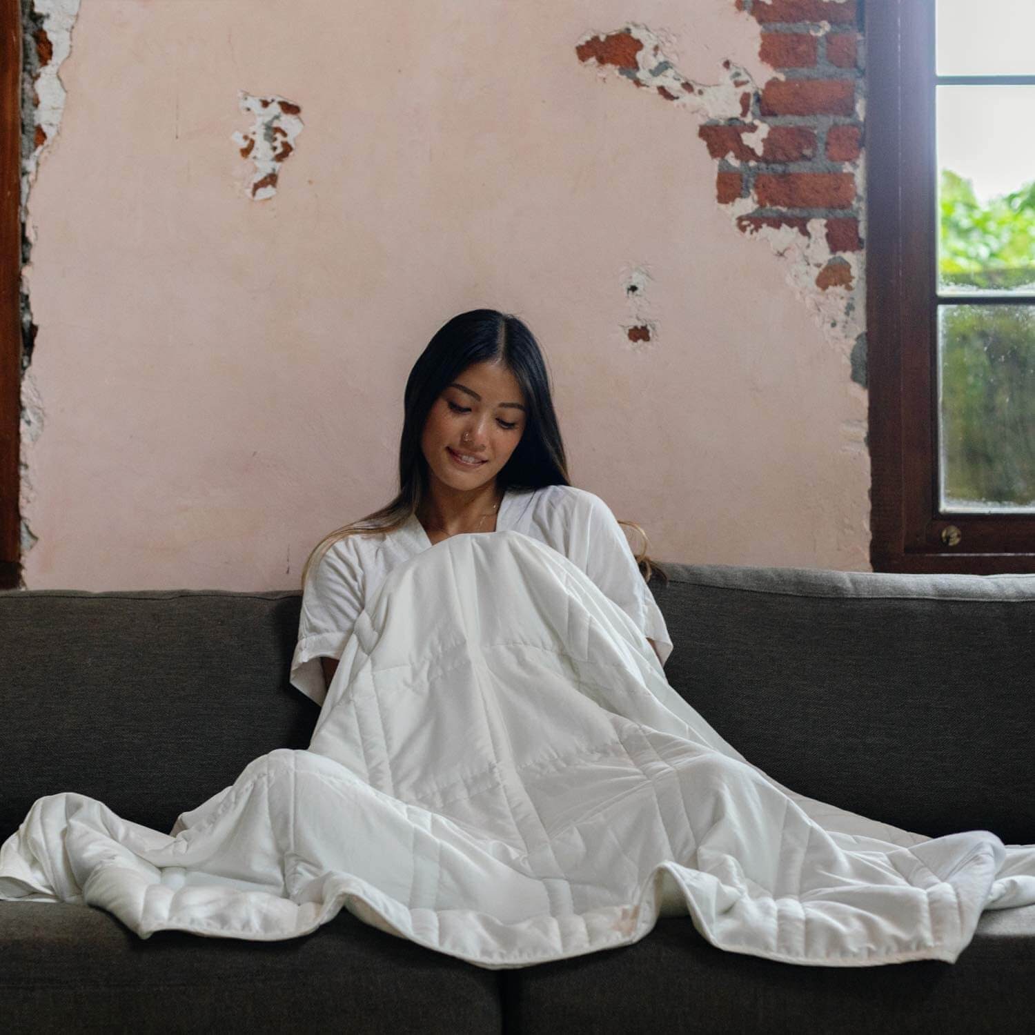 Woman wrapped up in weighted blanket on couch