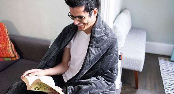Man reading while wrapped up in blanket