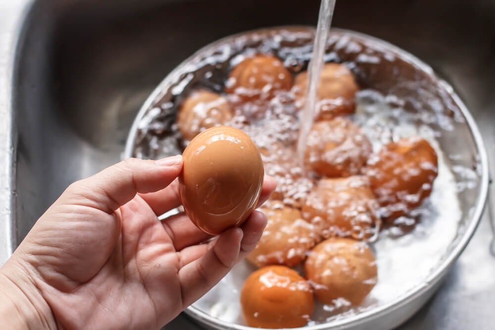 Woman holding egg over sink