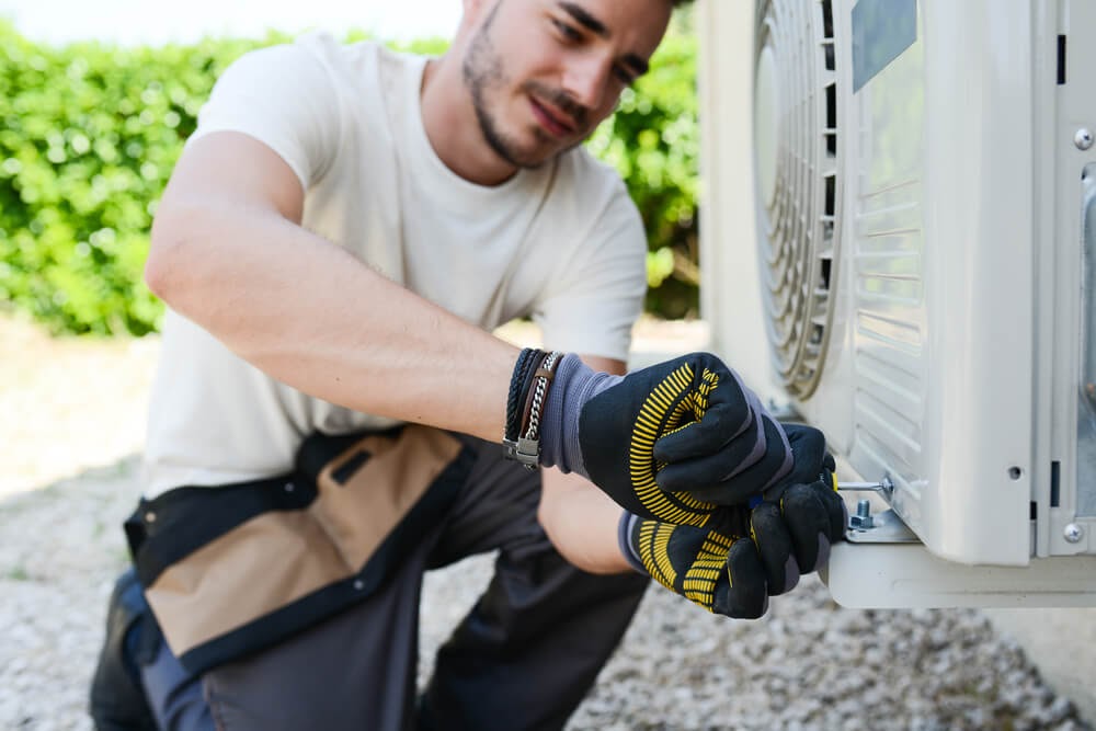 Man with gloves tightening a screw on an a/c unit cover