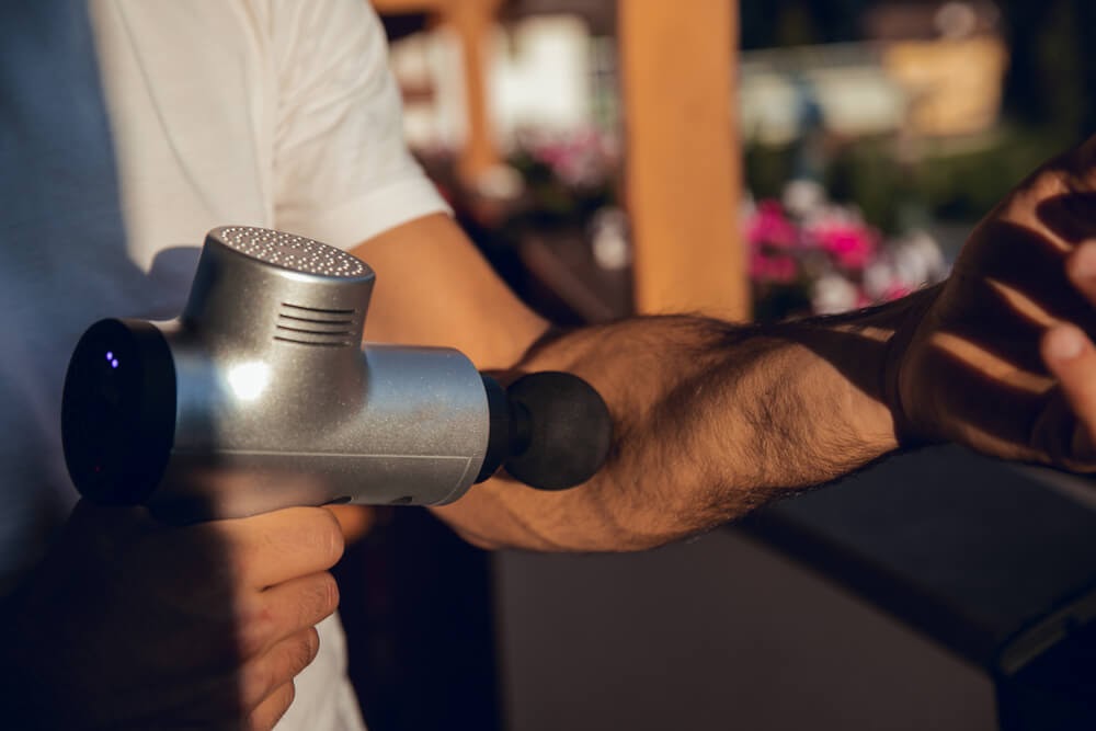 Man using a massage gun on his forearm