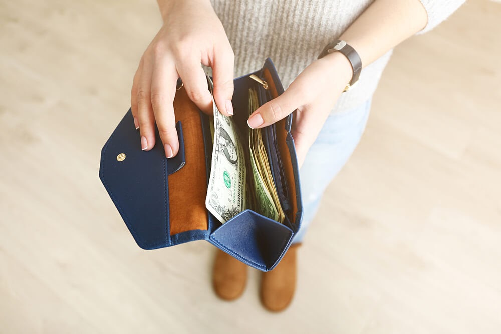 Woman pulling cash out of her wallet