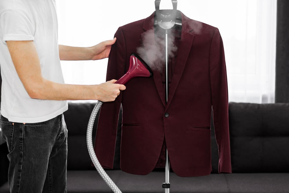 Man steam cleaning a rad maroon suit