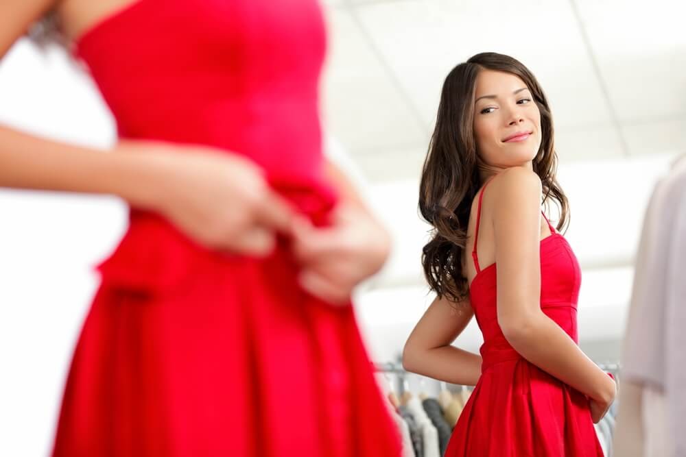 Woman looking fabulous in a red dress and admiring herself in a mirror