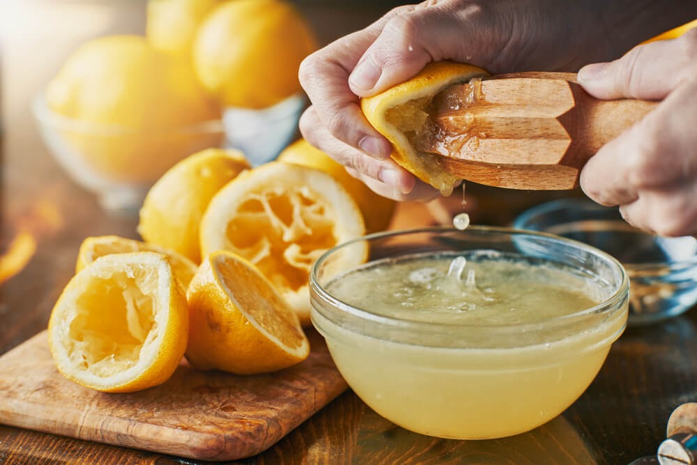 Juicing lemons into bowl in a sun-filled room.