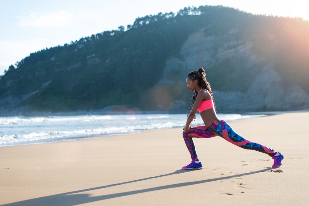 Woman looking fierce while lunging on a beach