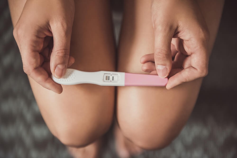 Woman looking over positive pregnancy test