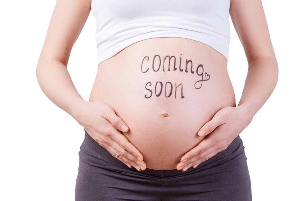 Woman with "Coming Soon" written on her pregnant belly