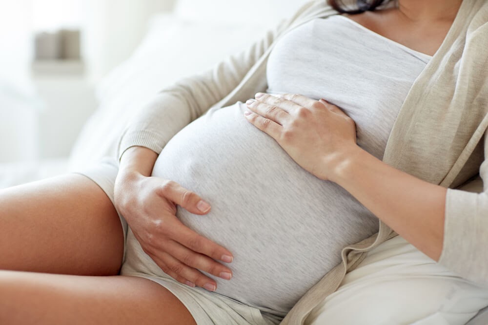 Woman relaxing on a couch and holding her belly
