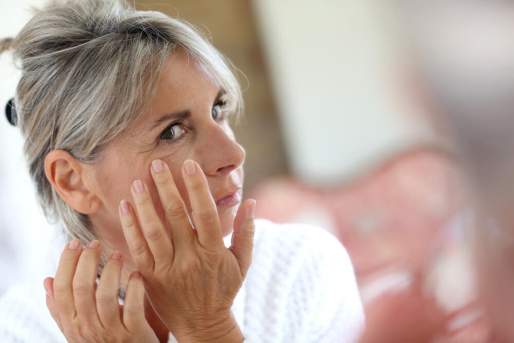 Woman looking at her face in the mirror