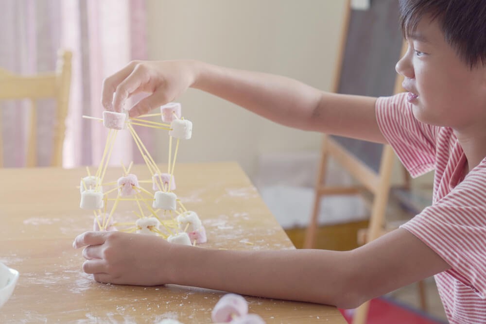 Child building something out of noodles and marshmallows