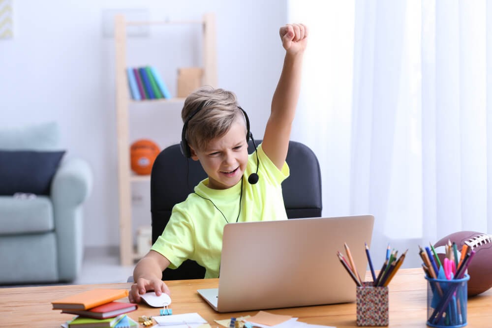 Boy on the computer with arm up in triumph