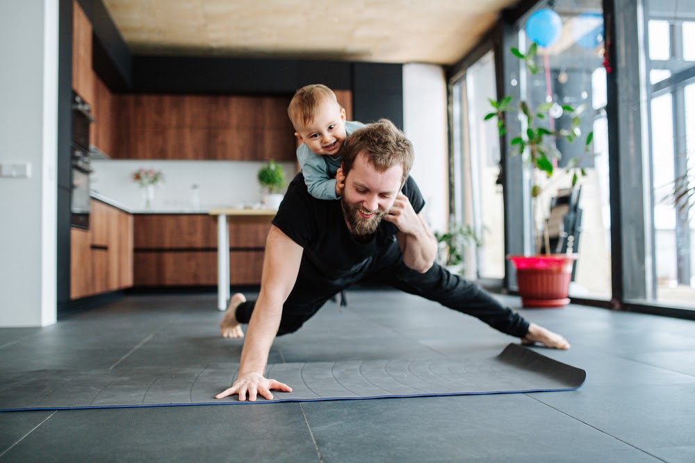 Man doing a one armed pushup with his son on his back