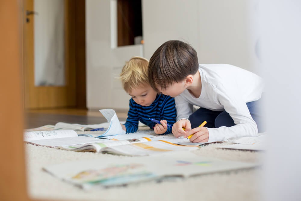 Two boys on the floor looking over some papers and books