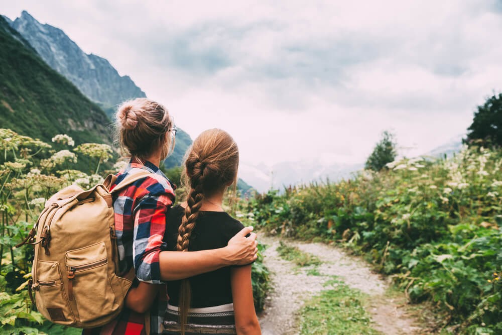Woman and teenage daughter looking back at the scenery while on a hike