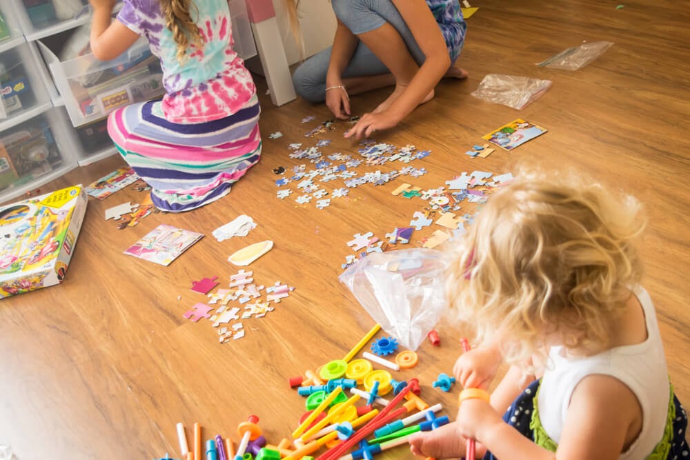 Sisters playing with puzzles and other learning toys on the floor