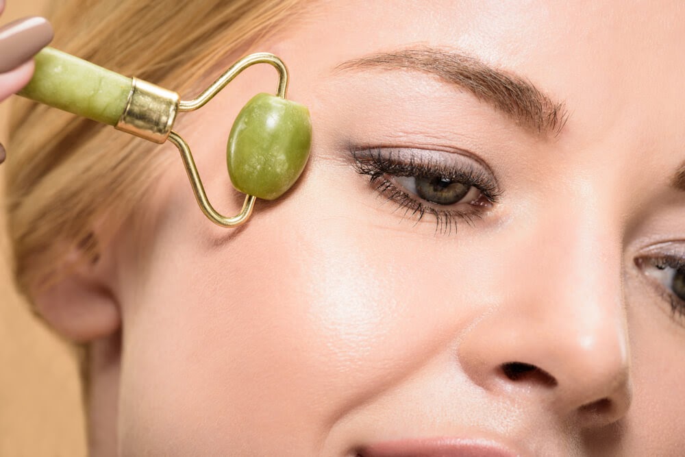 Woman using a jade roller on her face