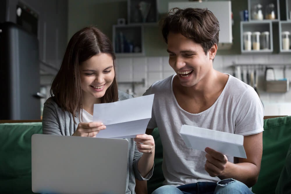 Guy and gal looking happily at their mail