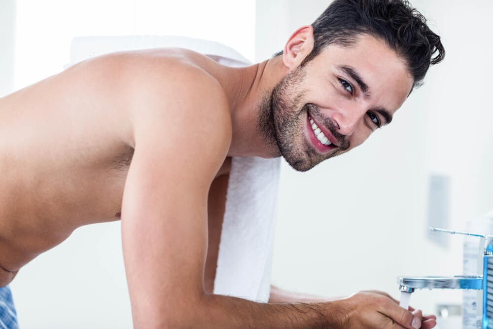 Shirtless man smiling at the camera in his bathroom