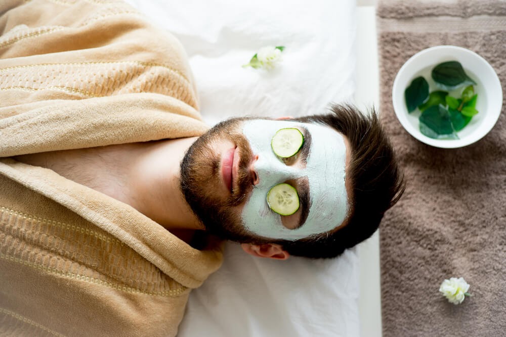 Man with a face mask with cucumbers on his eyes