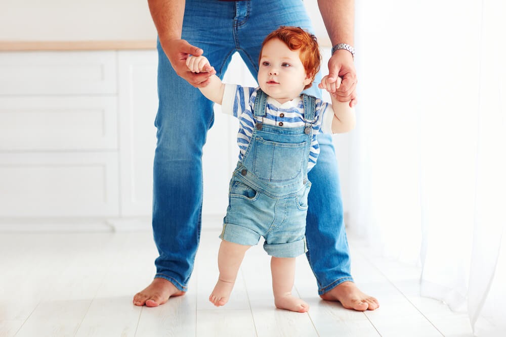 Dad holding his baby's hands, helping him walk