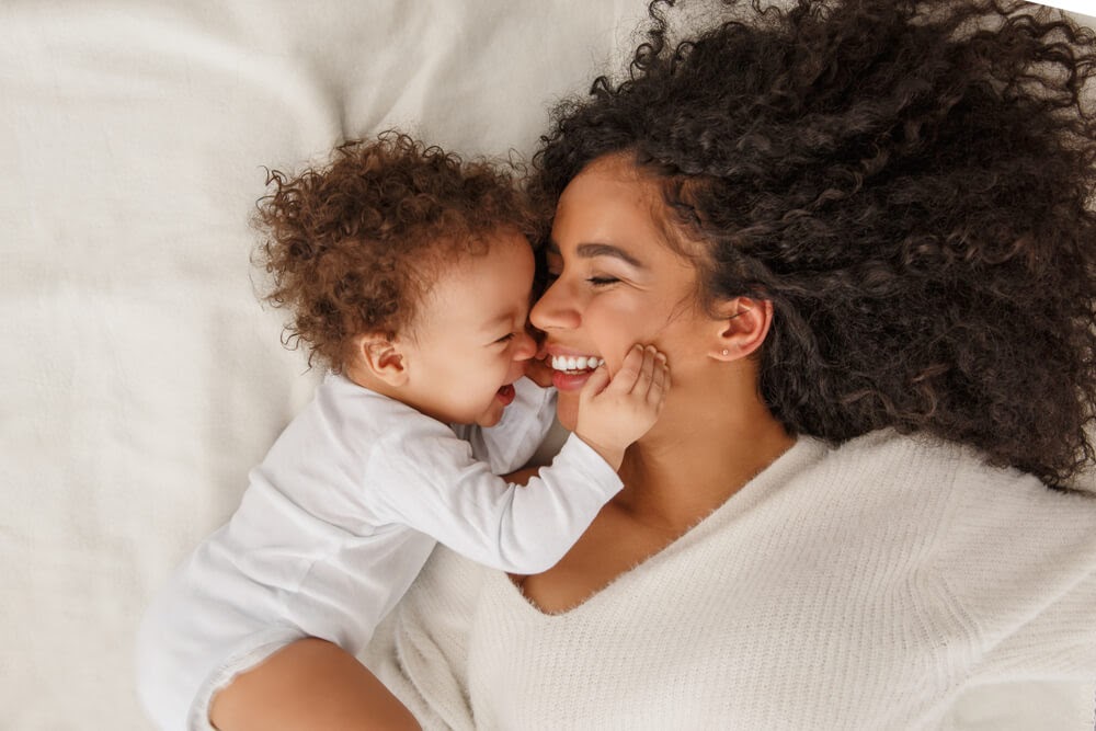 Mom and baby laughing in bed