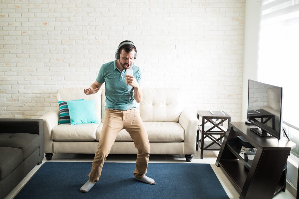 Man singing in his living room, using his phone as a microphone