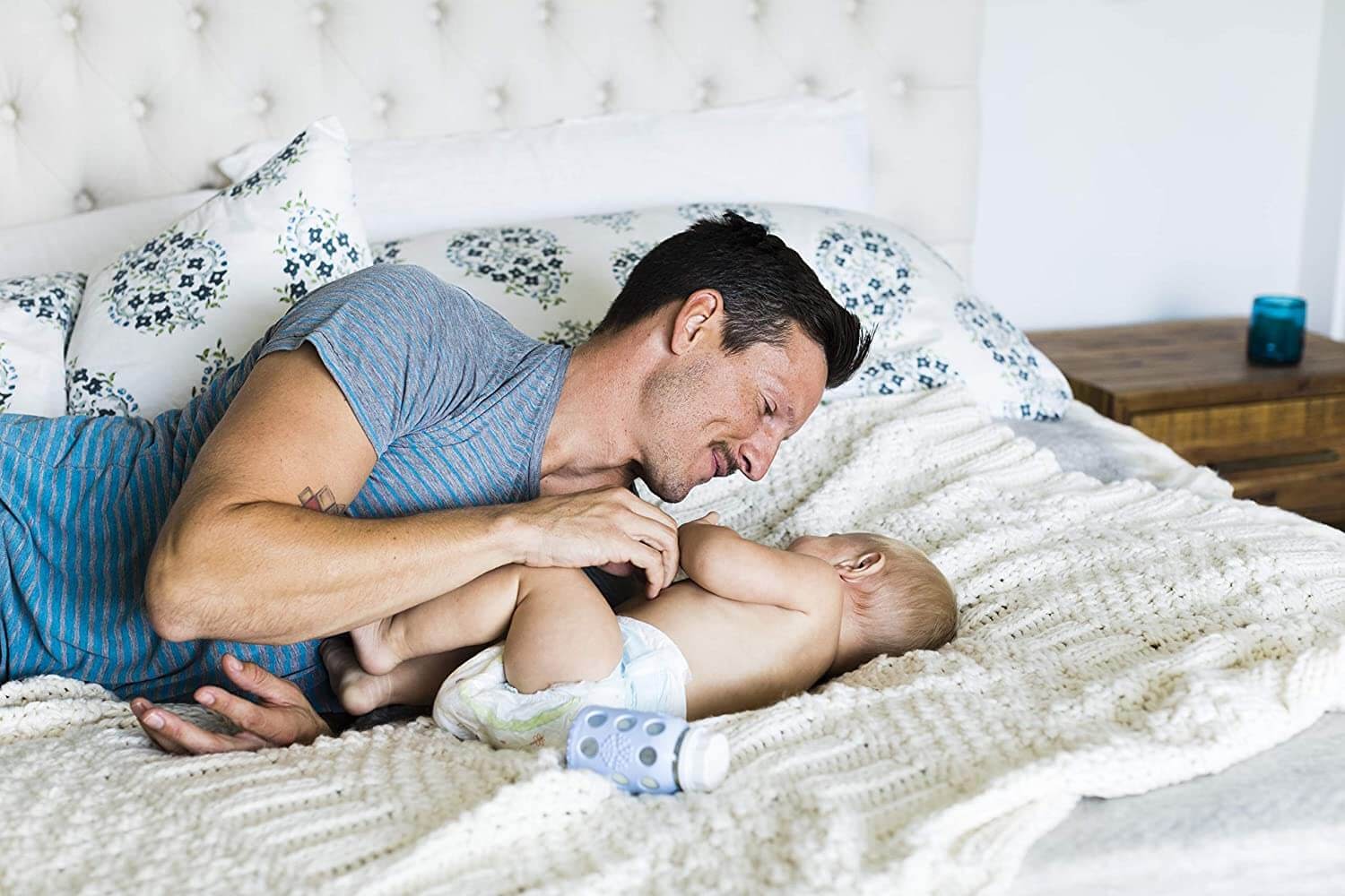 Dad and baby playing on their bed with bottle nearby