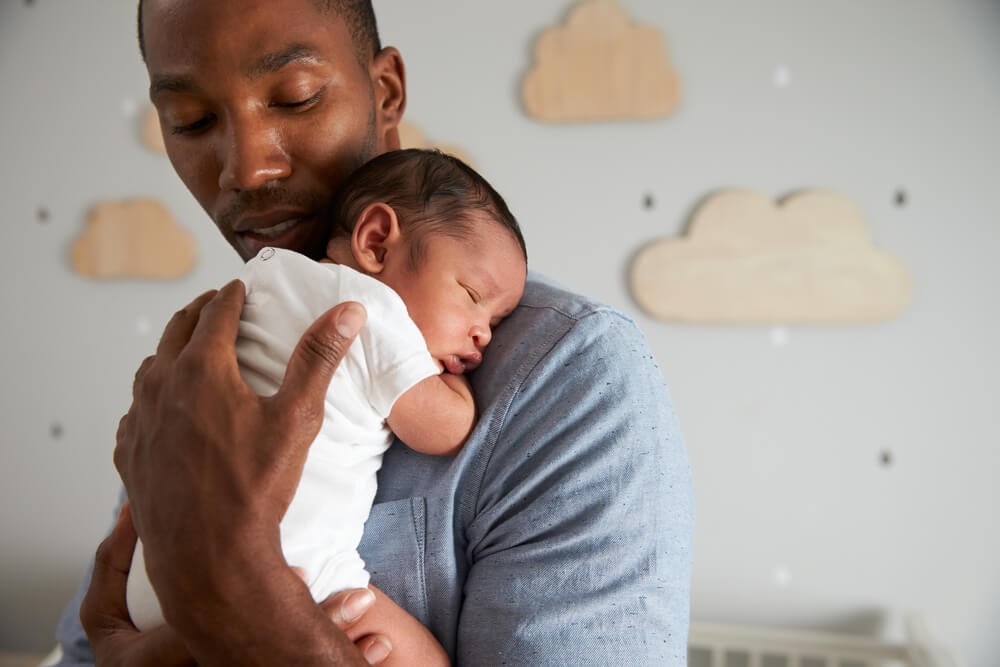 Man holding sleeping newborn
