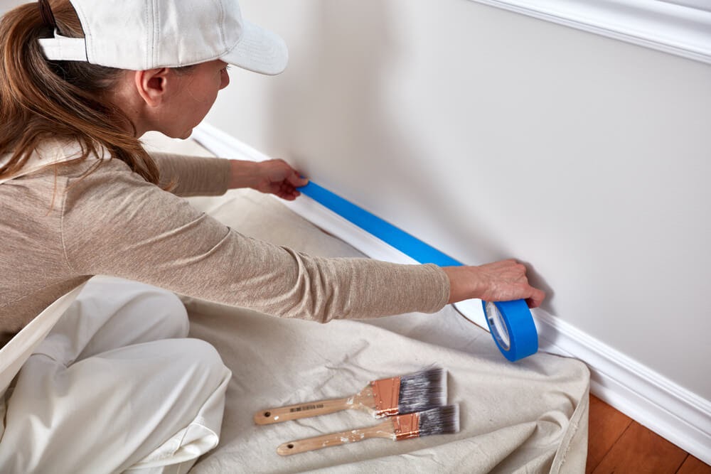 Woman taping off her wall trim