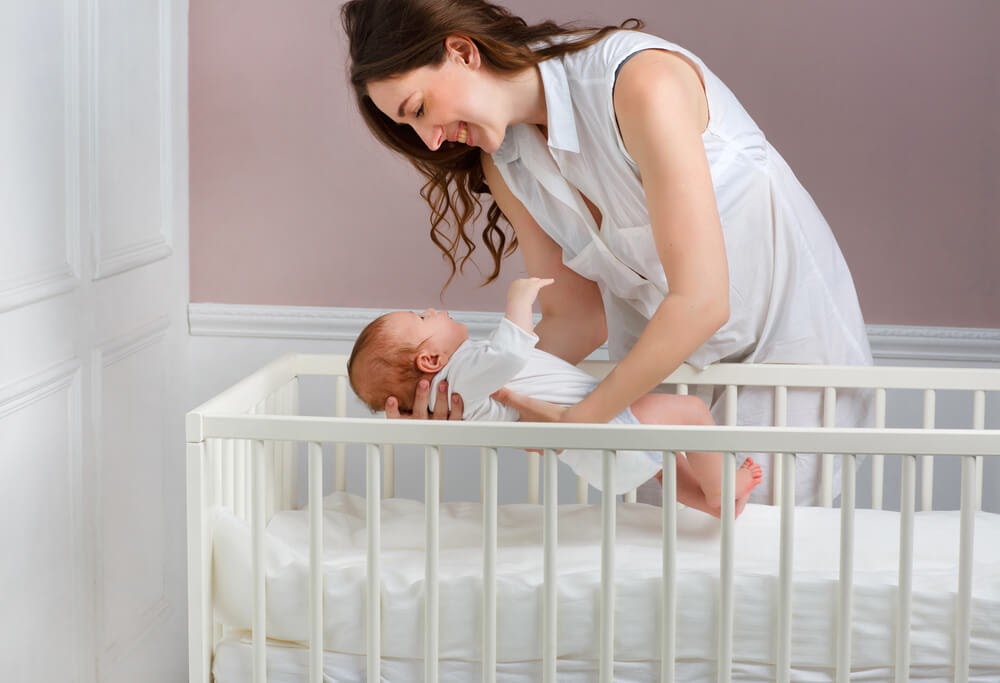 Mom laying her baby down in a crib
