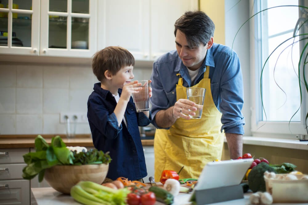 Father and son drinking water in their kitchen
