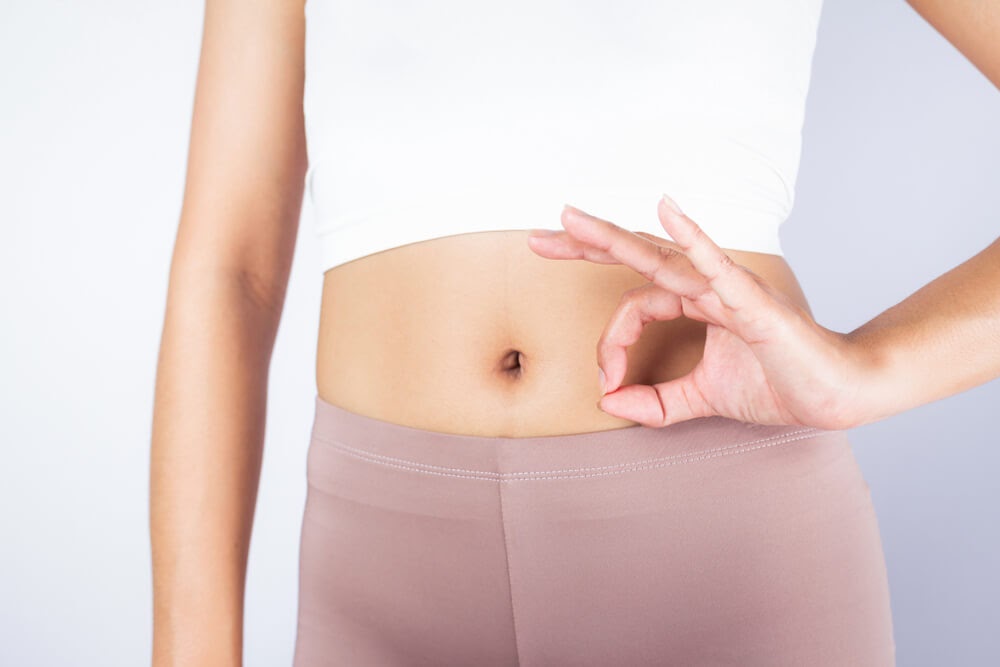 Woman holding "Ok" symbol with her hands over her belly