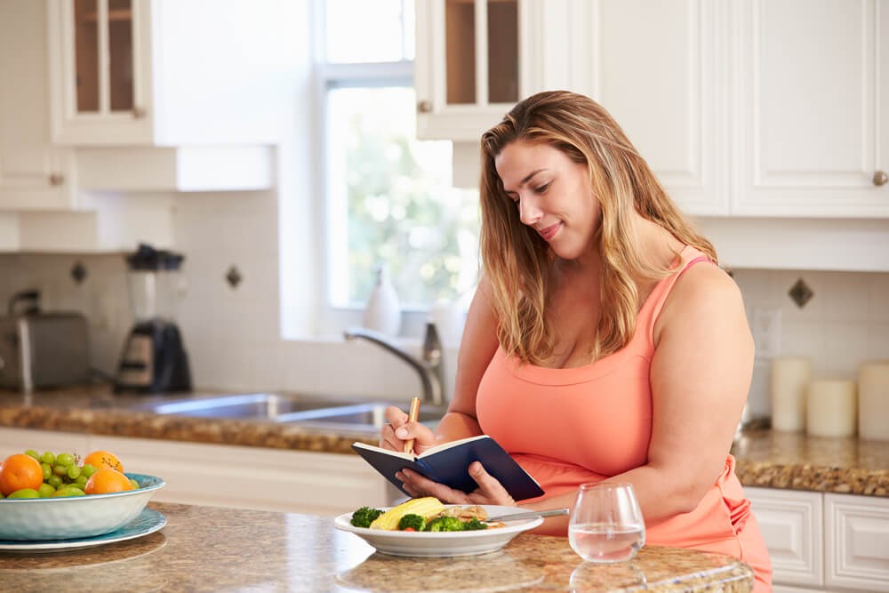 Woman writing in journal in her kitchen