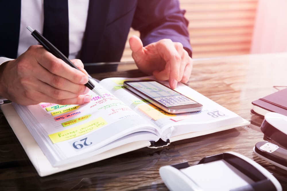 Close up of man sorting through his calendar and palm pilot