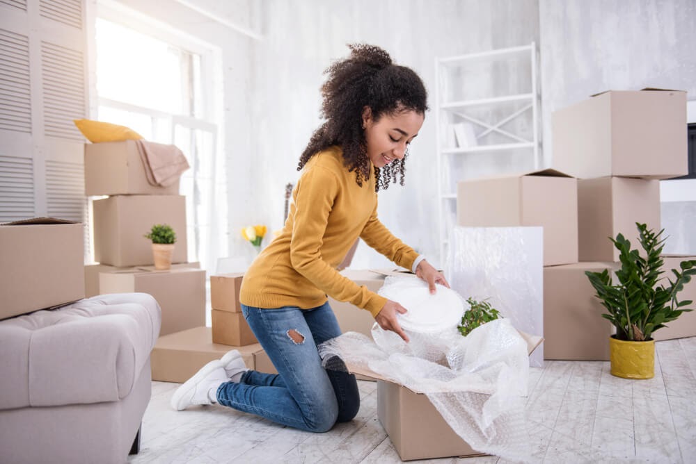 Gal opening a box of dishes in her living room