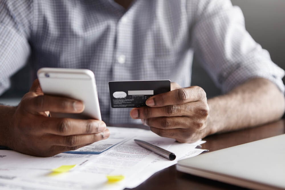Man holding his phone and credit card
