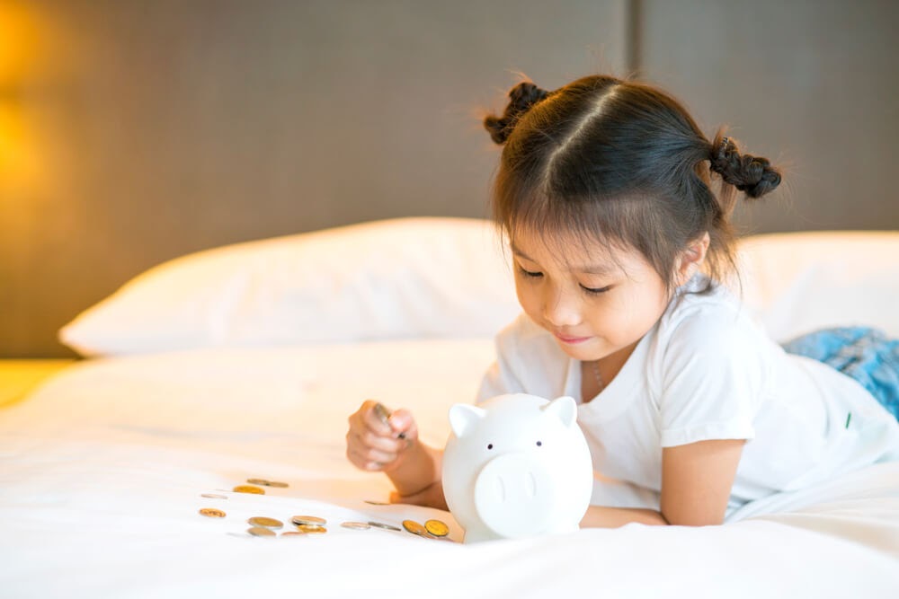 Girl counting her pennies in her piggy bank