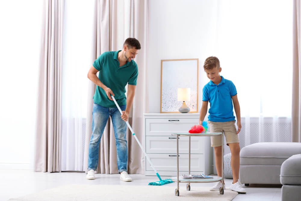 Father and son dusting the living room together