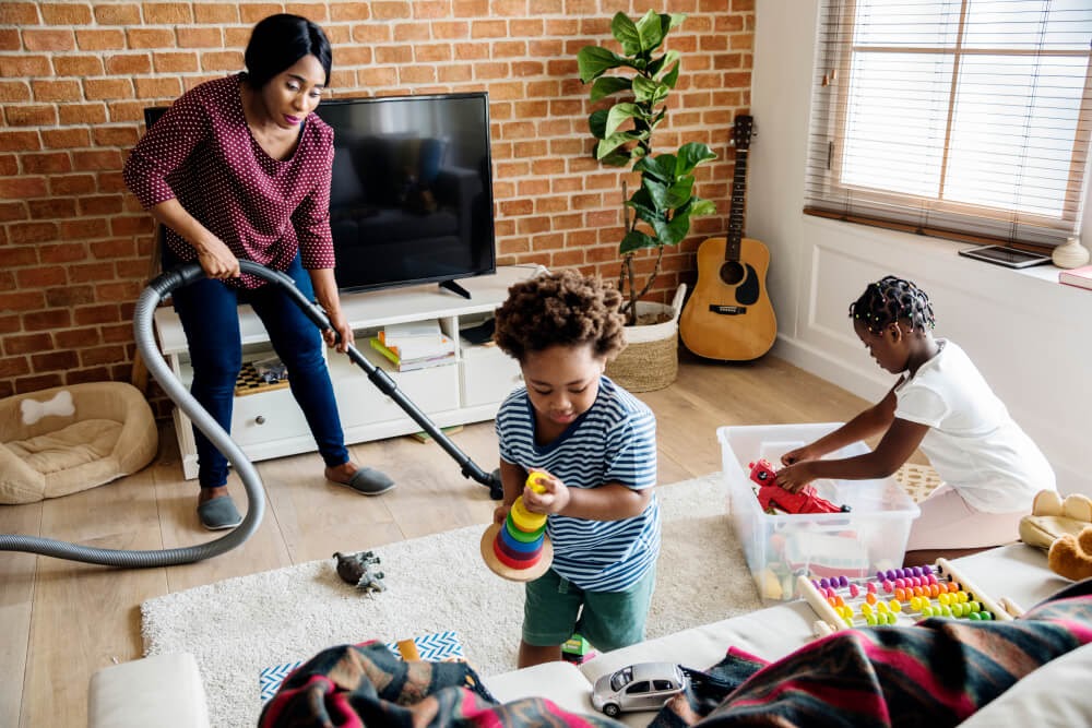 Mom vacuuming while children play