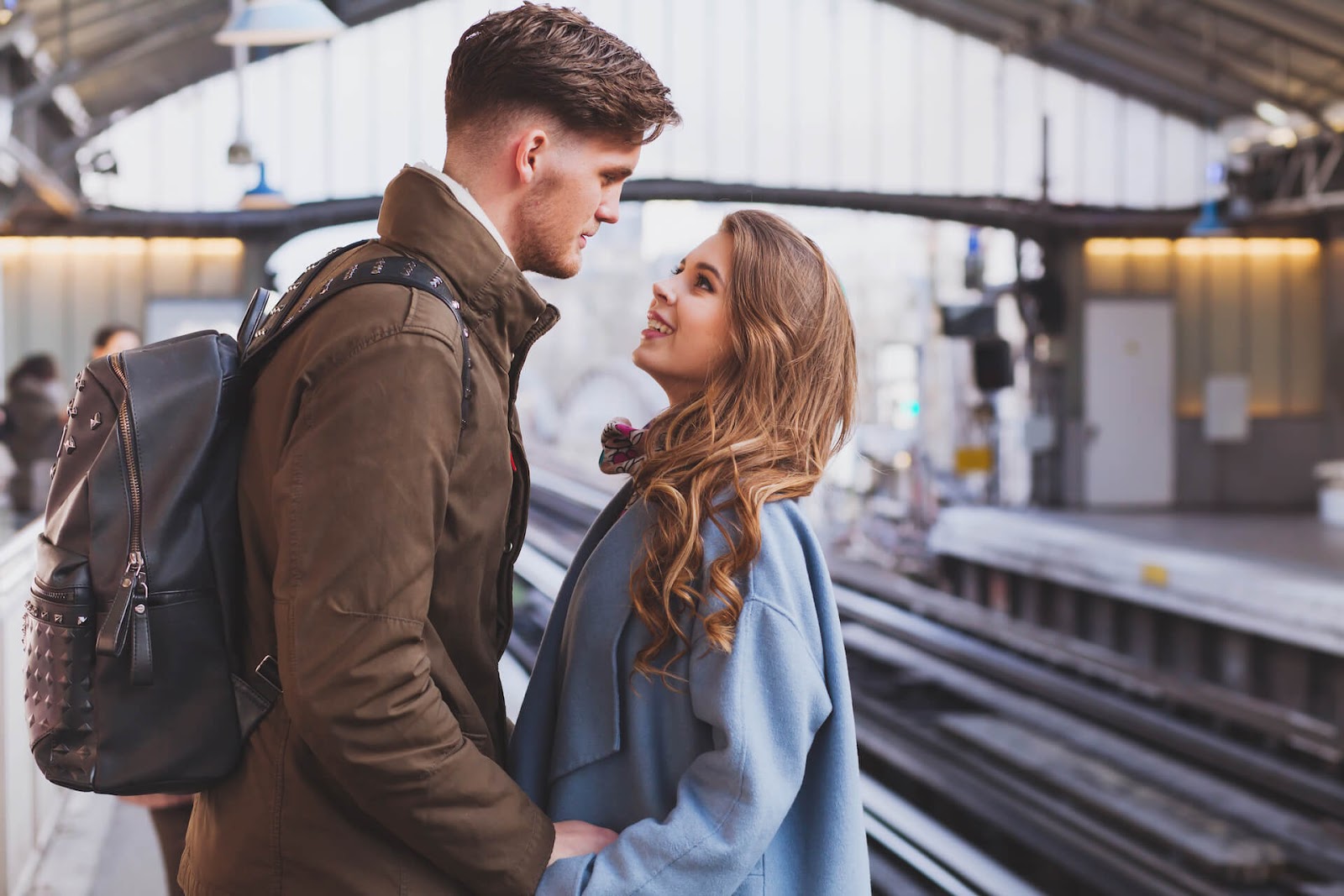 Man and woman looking longingly into each other's eyes at a train station