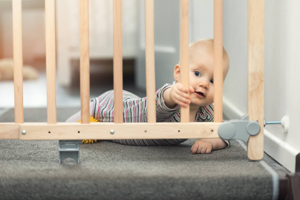 Baby looking trough a wooden baby gate