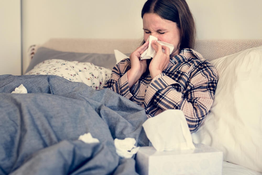 Woman blowing her nose in bed