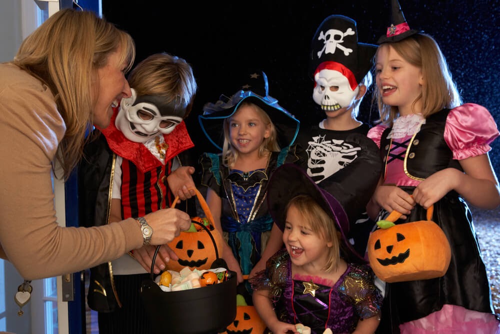 Woman handing out candy to group of trick or treaters