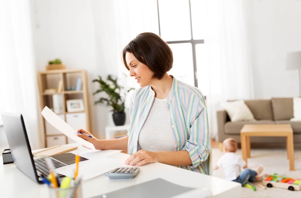Woman looking over her financial statements in front of a laptop