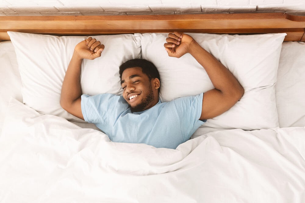 Man stretching in bed after a good night sleep