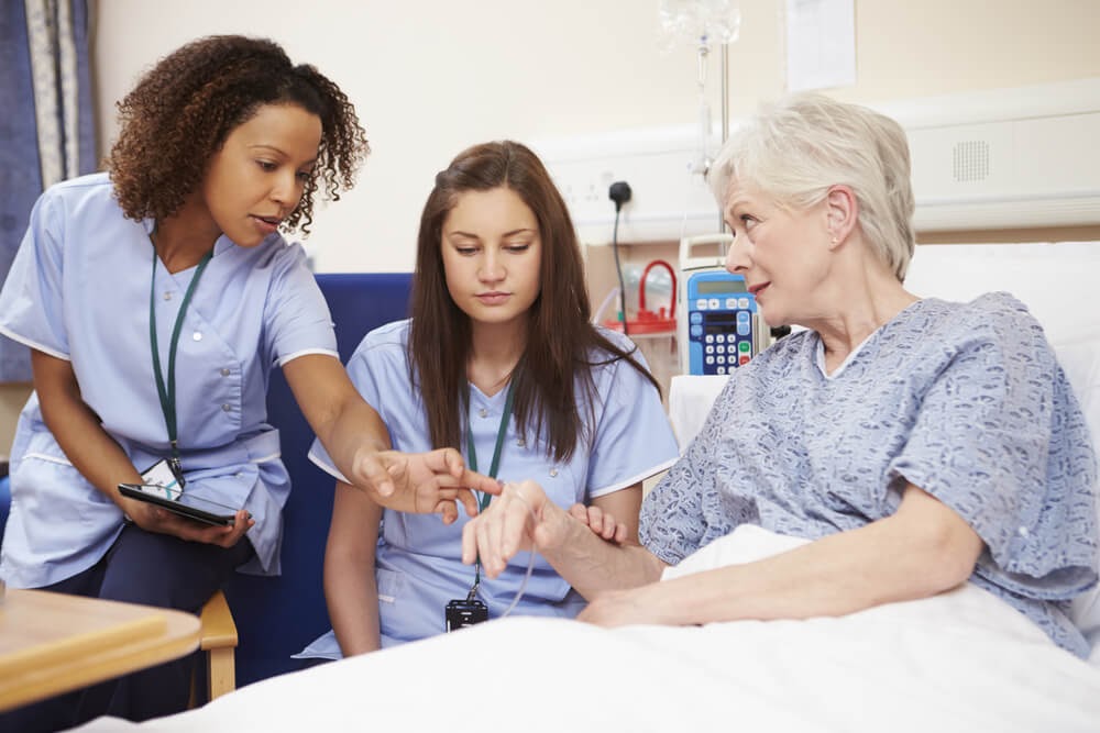 Two nurses helping an older woman